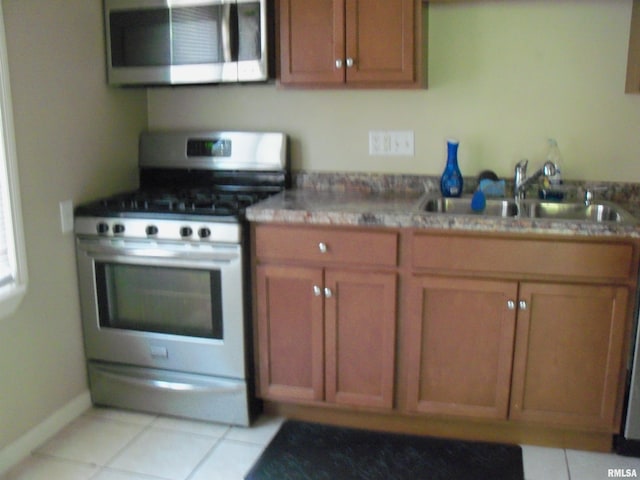 1003 S Johnson Ave, Carbondale, IL 62901 - kitchen featuring brown cabinetry, light tile patterned flooring, stainless steel appliances, and a sink