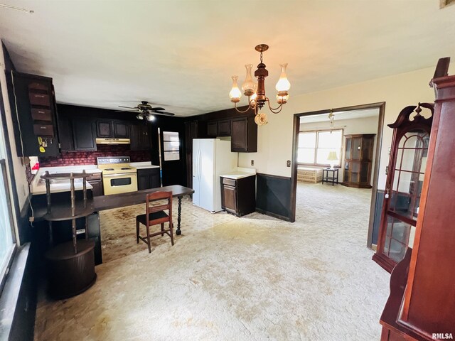 kitchen with ceiling fan with notable chandelier, white appliances, pendant lighting, light colored carpet, and under cabinet range hood