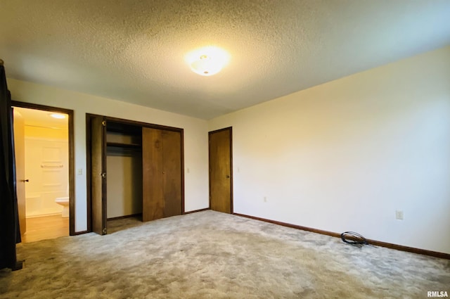 214 W Locust St, Harrisburg, IL 62946 - unfurnished bedroom featuring a textured ceiling, ensuite bathroom, baseboards, carpet, and a closet