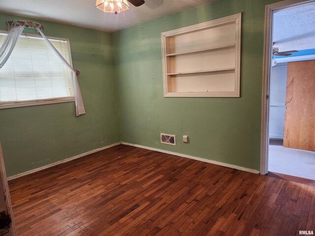 unfurnished room with ceiling fan, baseboards, wood finished floors, and visible vents