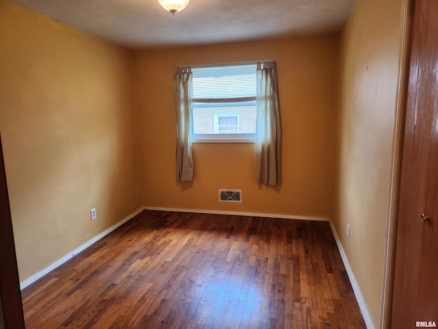 unfurnished room featuring baseboards, visible vents, and hardwood / wood-style flooring
