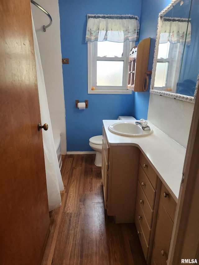 bathroom featuring baseboards, wood finished floors, vanity, and toilet