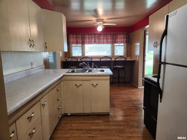 kitchen featuring range with electric stovetop, light countertops, a sink, dark wood-type flooring, and freestanding refrigerator