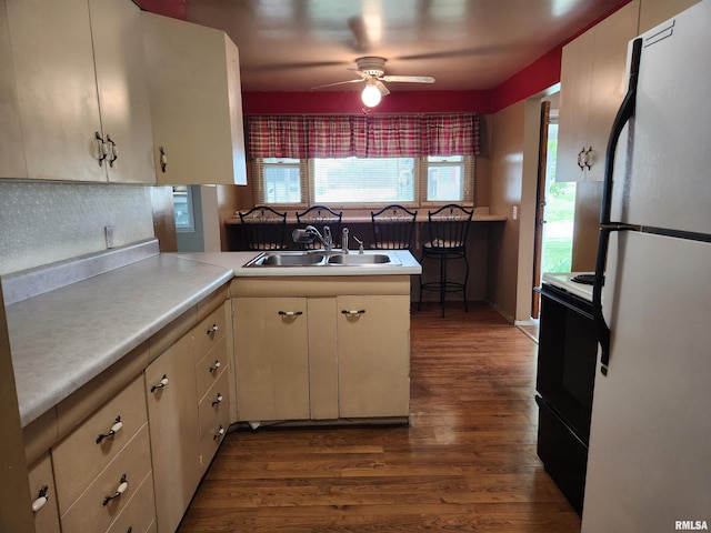 kitchen with range with electric cooktop, a sink, dark wood-type flooring, freestanding refrigerator, and a peninsula