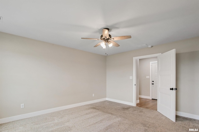 carpeted spare room with a ceiling fan and baseboards
