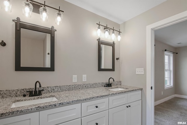 full bath with double vanity, baseboards, and a sink