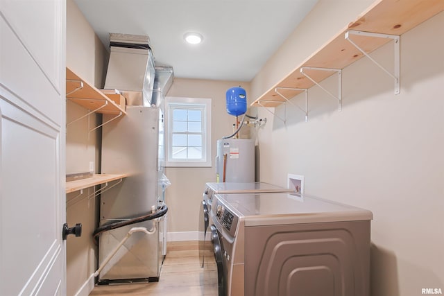 laundry area featuring electric water heater, light wood-style flooring, baseboards, laundry area, and independent washer and dryer