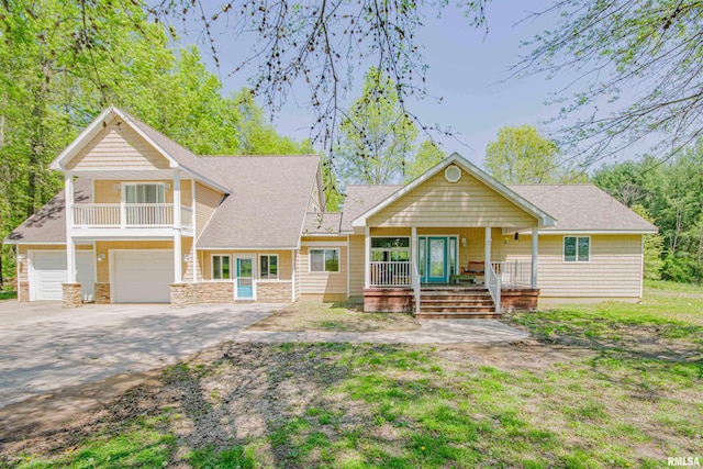 view of front of property with roof with shingles, an attached garage, a porch, a balcony, and driveway