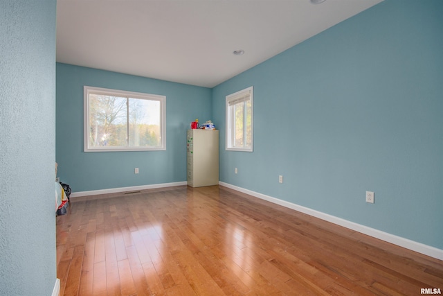 unfurnished room with baseboards, visible vents, and hardwood / wood-style flooring
