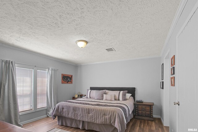102 E Woolcott St, Harrisburg, IL 62946 - bedroom with wood finished floors, visible vents, crown molding, baseboards, and a textured ceiling