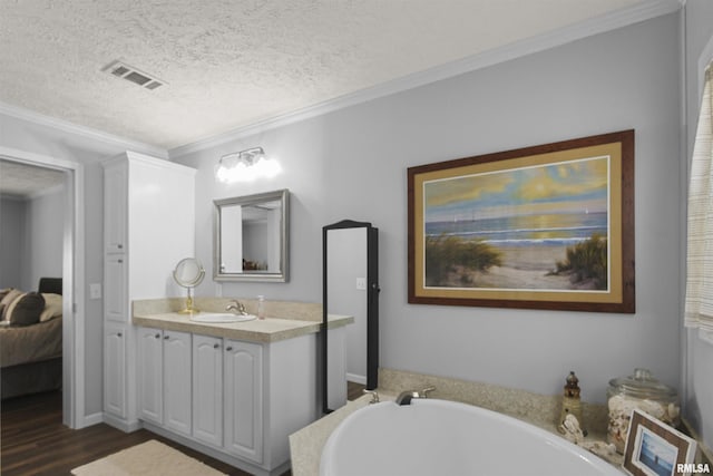 102 E Woolcott St, Harrisburg, IL 62946 - bathroom featuring a bath, a textured ceiling, visible vents, wood finished floors, and crown molding