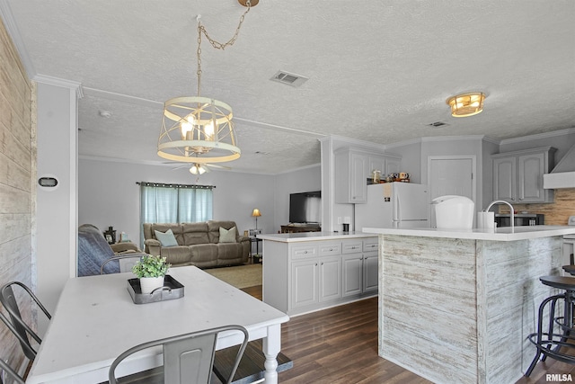 102 E Woolcott St, Harrisburg, IL 62946 - kitchen featuring a breakfast bar area, light countertops, dark wood finished floors, visible vents, and freestanding refrigerator