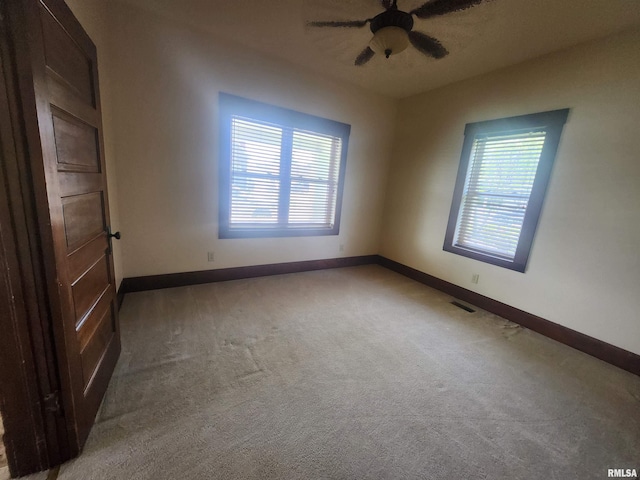 empty room featuring light carpet, visible vents, and baseboards