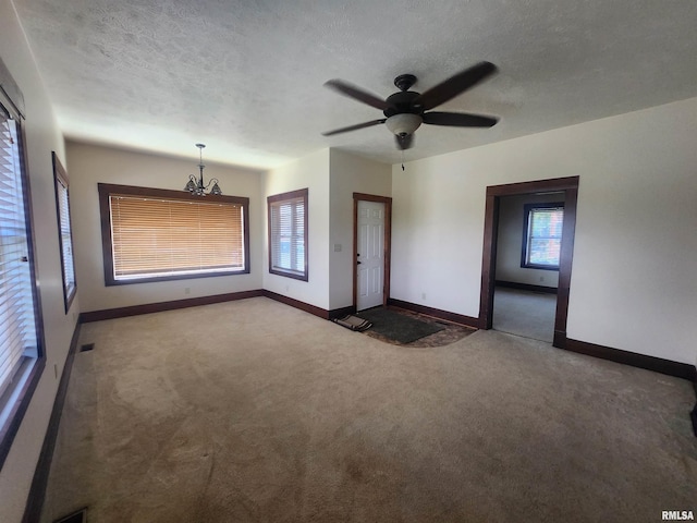 unfurnished living room with ceiling fan with notable chandelier, baseboards, carpet flooring, and visible vents