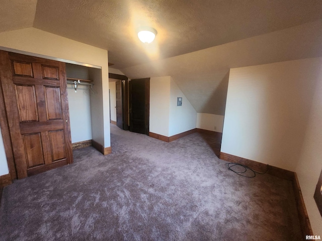 bonus room with vaulted ceiling, baseboards, dark carpet, and a textured ceiling