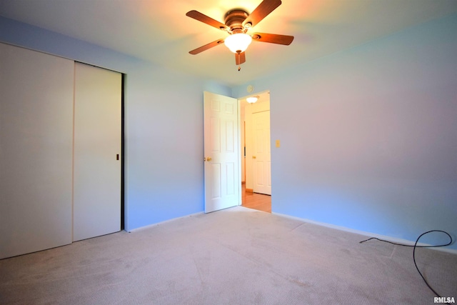 unfurnished bedroom with ceiling fan, light carpet, and a closet