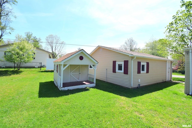 back of house featuring an outdoor structure, a yard, and a shed