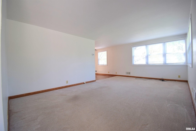 spare room with carpet floors, visible vents, and baseboards
