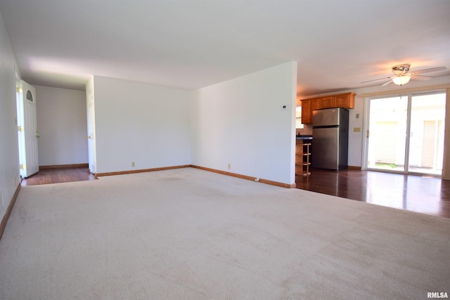 unfurnished living room featuring carpet, a ceiling fan, and baseboards