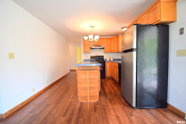 kitchen featuring freestanding refrigerator, black range with electric cooktop, dark wood-style flooring, and an inviting chandelier