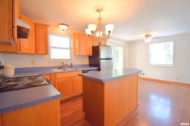 kitchen with a sink, stovetop, exhaust hood, visible vents, and freestanding refrigerator