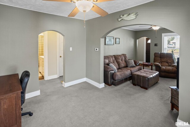carpeted living room with arched walkways, baseboards, and ceiling fan