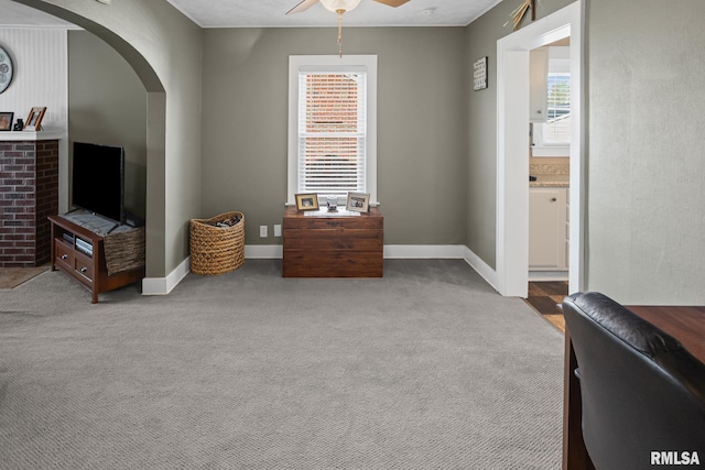sitting room featuring arched walkways, plenty of natural light, carpet floors, and ceiling fan