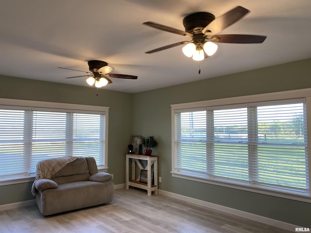sitting room with baseboards, a ceiling fan, and light wood-style floors