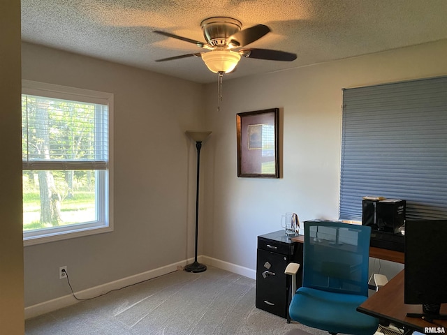 office featuring baseboards, a textured ceiling, light colored carpet, and ceiling fan
