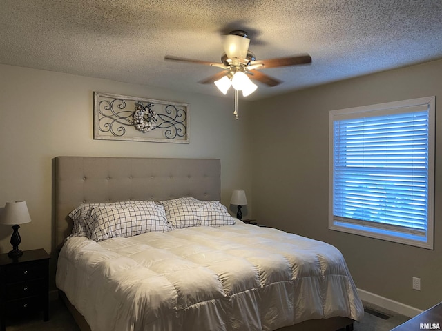 bedroom with a textured ceiling, visible vents, baseboards, and ceiling fan