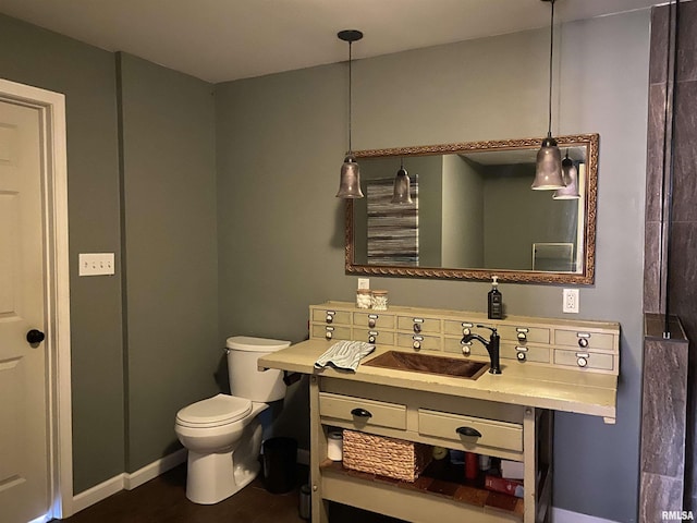 bathroom featuring toilet, vanity, and baseboards
