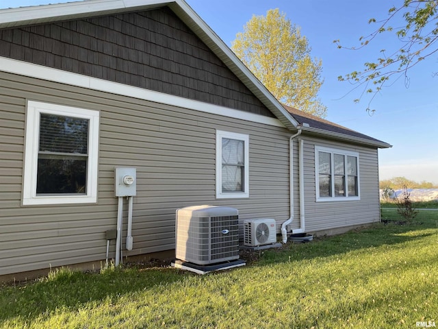 rear view of house with ac unit, a yard, and cooling unit