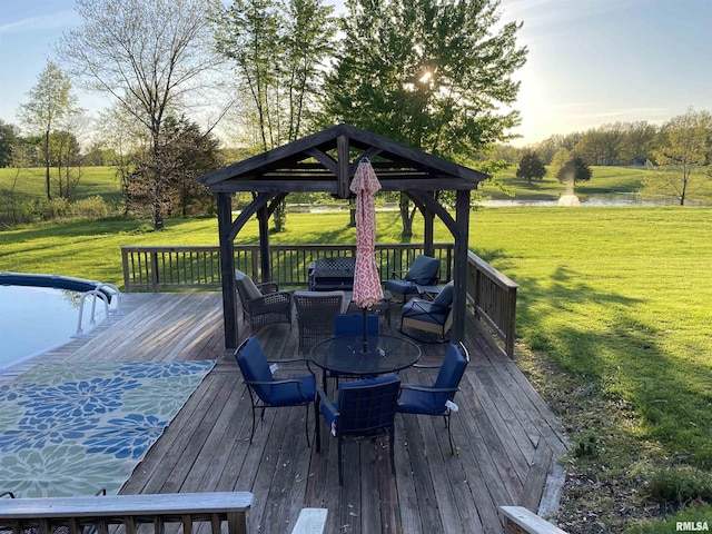 wooden terrace with a lawn, a gazebo, a water view, and outdoor dining area