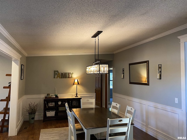 dining area featuring wainscoting, dark wood-style floors, a textured ceiling, and ornamental molding