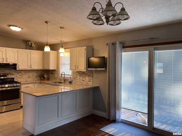kitchen featuring tasteful backsplash, a sink, a chandelier, white cabinets, and stainless steel range with gas stovetop