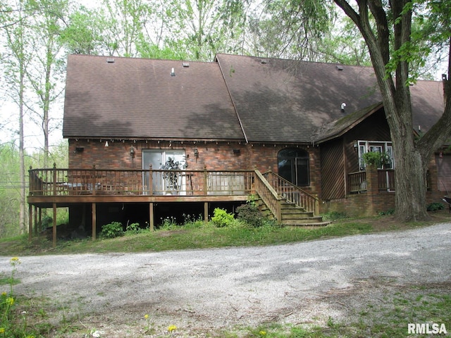 back of house featuring a wooden deck, roof with shingles, and brick siding