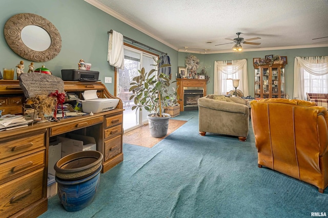 living room featuring a ceiling fan, a textured ceiling, a glass covered fireplace, carpet floors, and ornamental molding