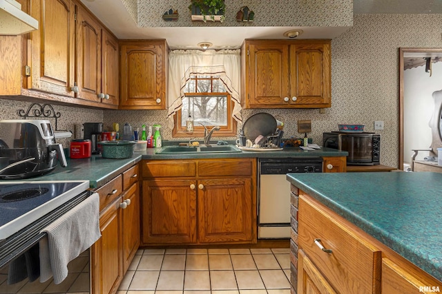 kitchen featuring brown cabinetry, dishwashing machine, a sink, and under cabinet range hood