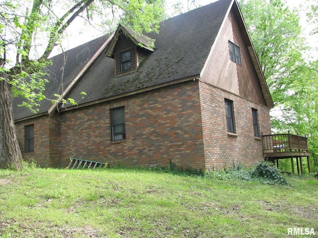 view of side of home with a lawn, brick siding, and a deck