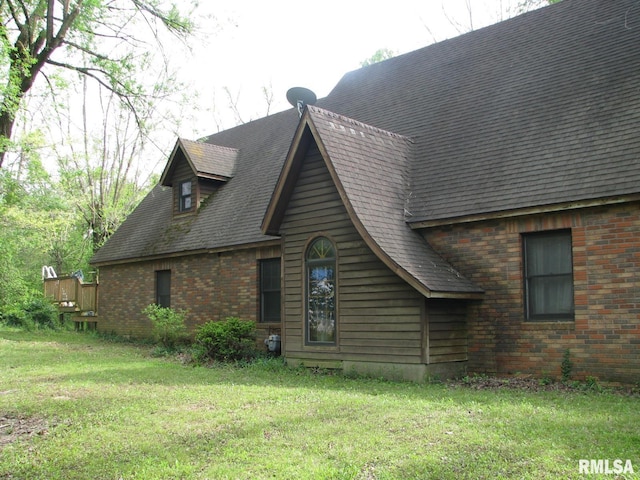 view of home's exterior with brick siding and a lawn