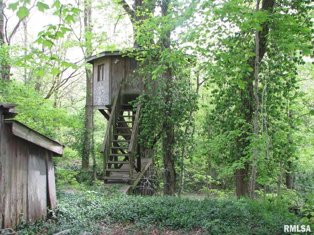 view of outbuilding featuring a forest view and stairs