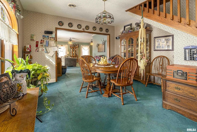 carpeted dining space with wallpapered walls, visible vents, a textured ceiling, and ceiling fan