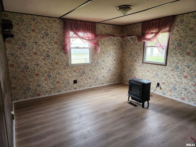 14625 E E Il Highway 15, Mount Vernon, IL 62864 - empty room with a healthy amount of sunlight, a wood stove, wood finished floors, and wallpapered walls