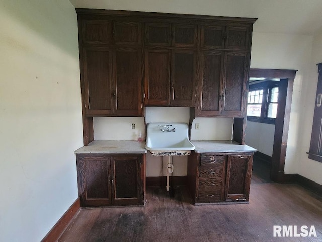 unfurnished office with baseboards, a sink, and dark wood-style floors