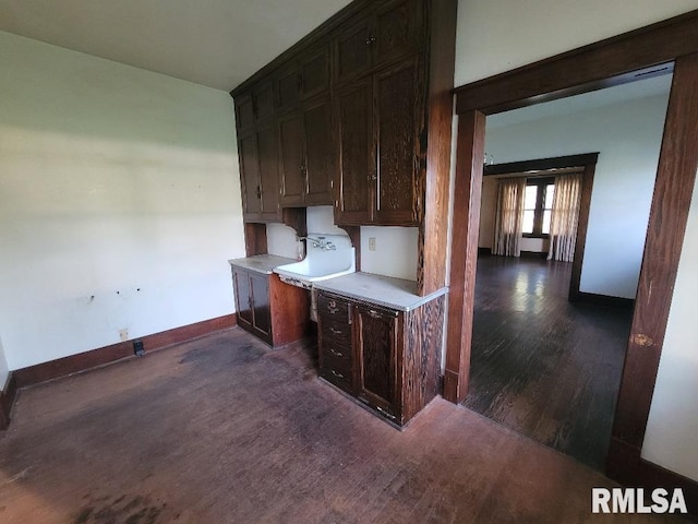 interior space with light countertops, baseboards, built in desk, and dark wood-style flooring