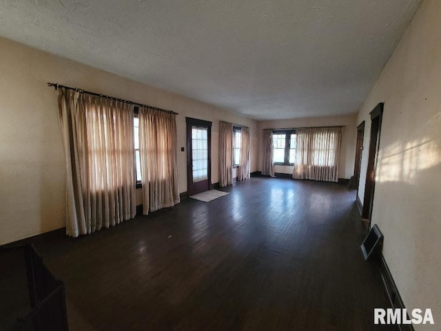 unfurnished living room featuring a textured ceiling and dark wood-style floors