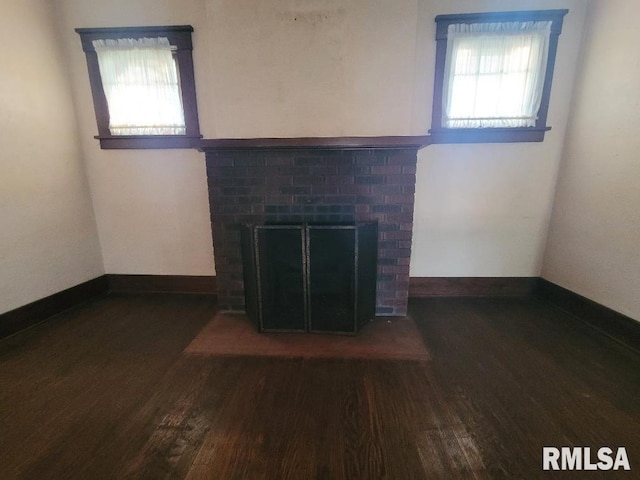 unfurnished living room with baseboards, wood finished floors, and a fireplace