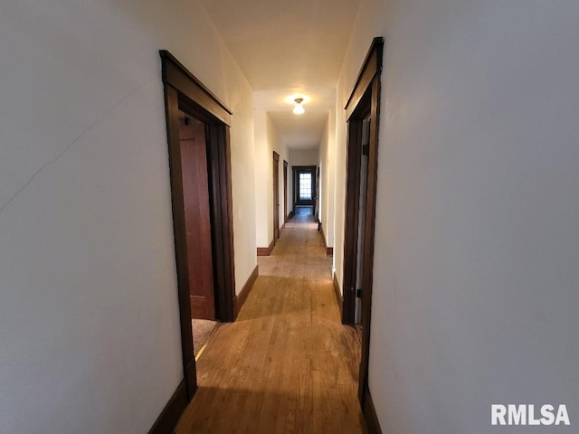 corridor with wood finished floors and baseboards