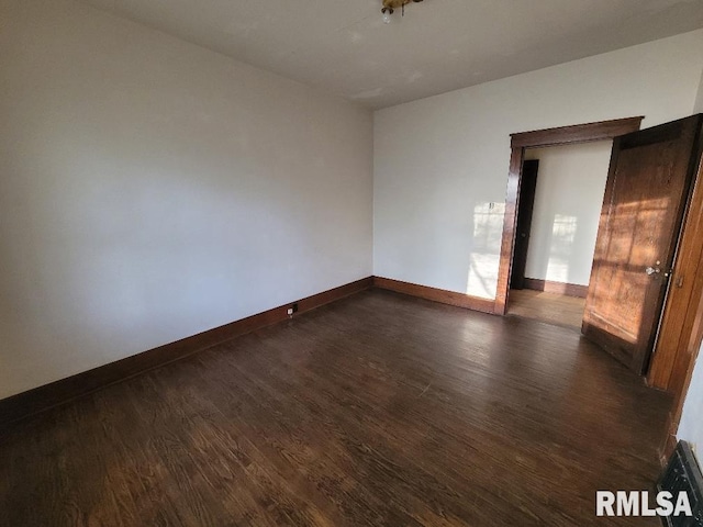 empty room featuring baseboards and dark wood-style flooring