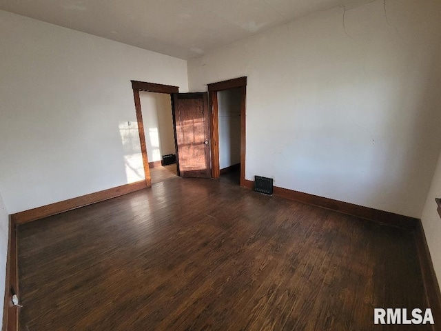 spare room featuring baseboards and dark wood-style flooring